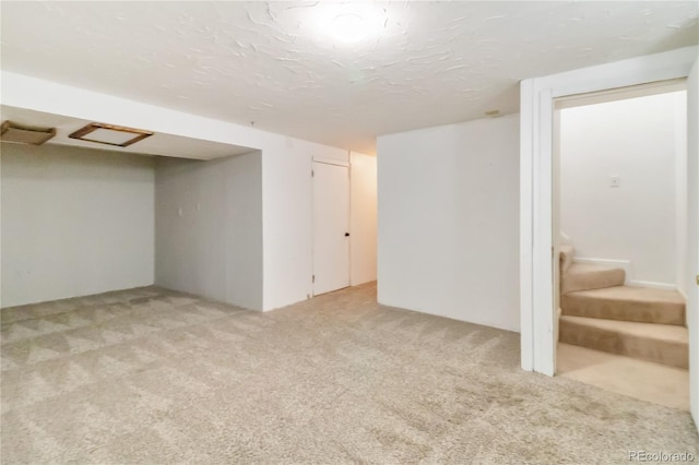 below grade area with stairway, a textured ceiling, and carpet flooring