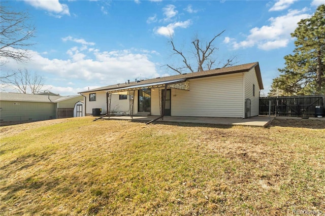 rear view of property with fence, a storage shed, a yard, a patio area, and an outbuilding