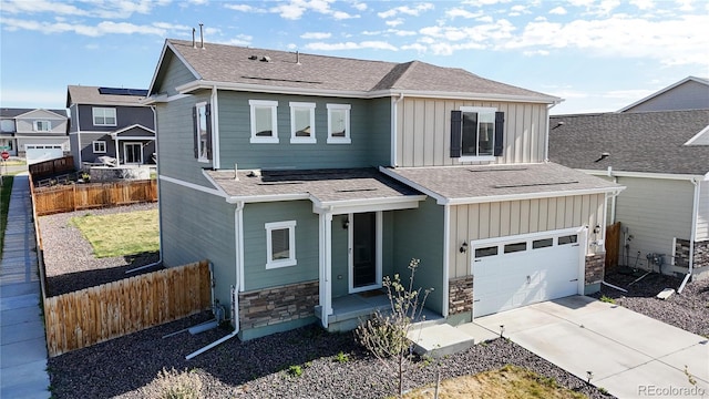 view of front of property with board and batten siding, fence, stone siding, concrete driveway, and a garage