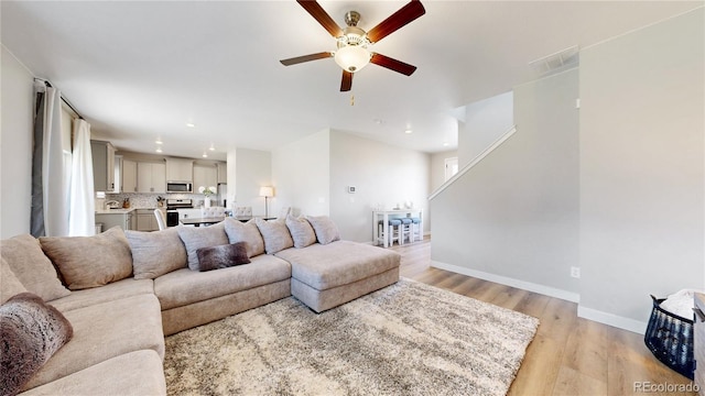 living room featuring a ceiling fan, light wood-type flooring, recessed lighting, and baseboards