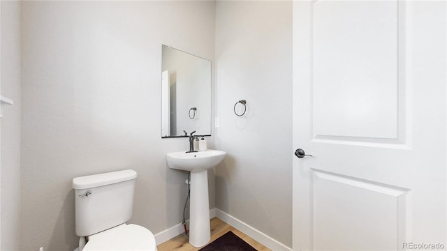 half bath featuring toilet, baseboards, and wood finished floors