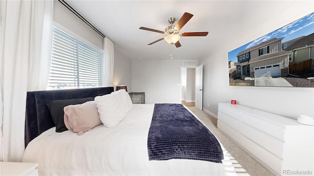 bedroom with ceiling fan, light colored carpet, and baseboards