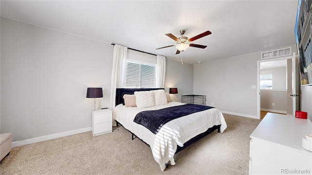 bedroom featuring multiple windows, light carpet, and baseboards