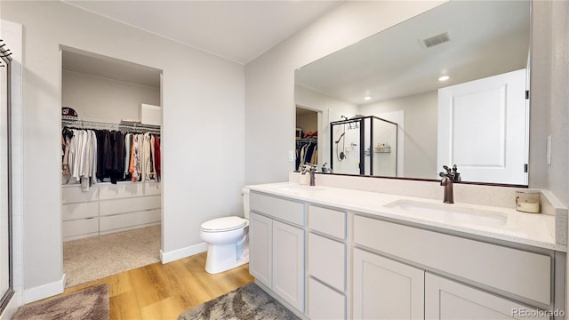 17947 E 95th Ave, Commerce City, CO 80022 - bathroom featuring a walk in closet, a stall shower, wood finished floors, toilet, and double vanity
