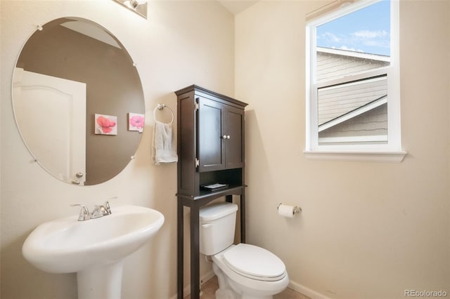 bathroom with toilet, a sink, and baseboards