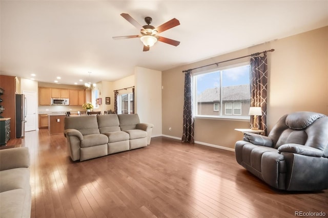 living room featuring hardwood / wood-style floors, a ceiling fan, baseboards, and recessed lighting