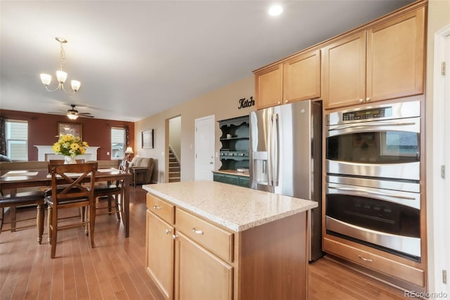 kitchen featuring appliances with stainless steel finishes, a chandelier, a center island, light wood finished floors, and open floor plan