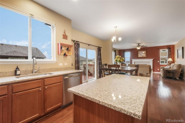 kitchen featuring a sink, dishwasher, light stone counters, open floor plan, and ceiling fan