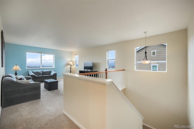 corridor with carpet flooring, healthy amount of natural light, an upstairs landing, and baseboards