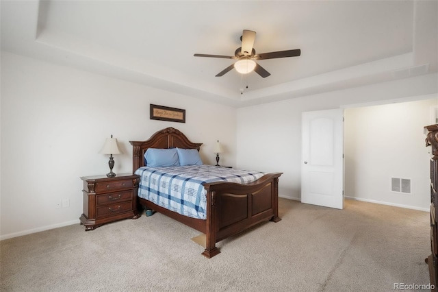 bedroom with a raised ceiling, light carpet, baseboards, and ceiling fan