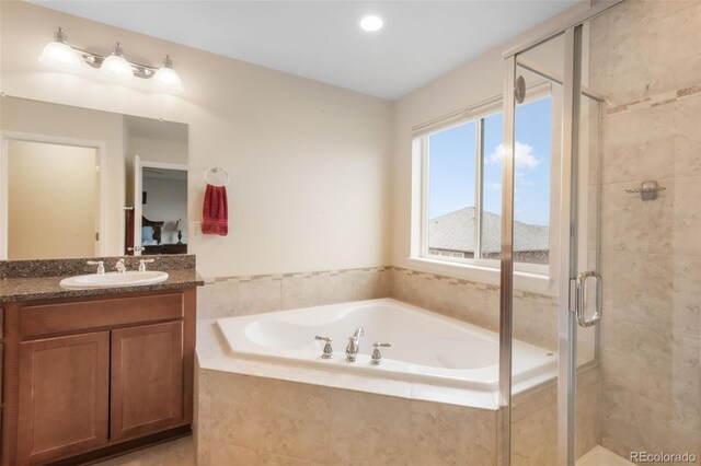 bathroom featuring a stall shower, a garden tub, and vanity