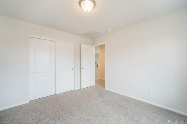 unfurnished bedroom with attic access, carpet, baseboards, and a closet