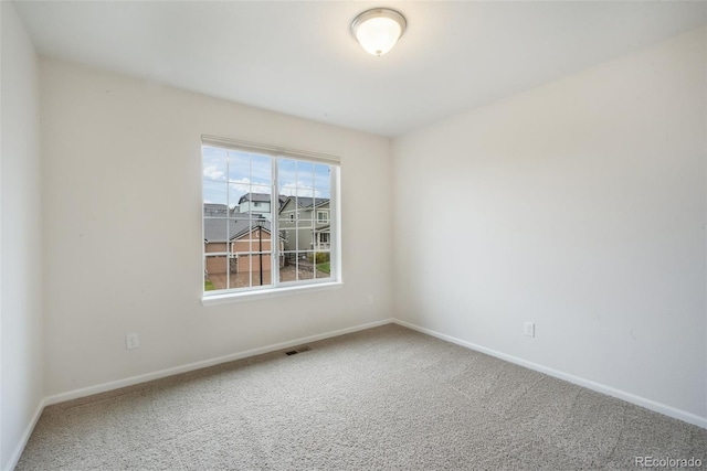 spare room featuring carpet and baseboards