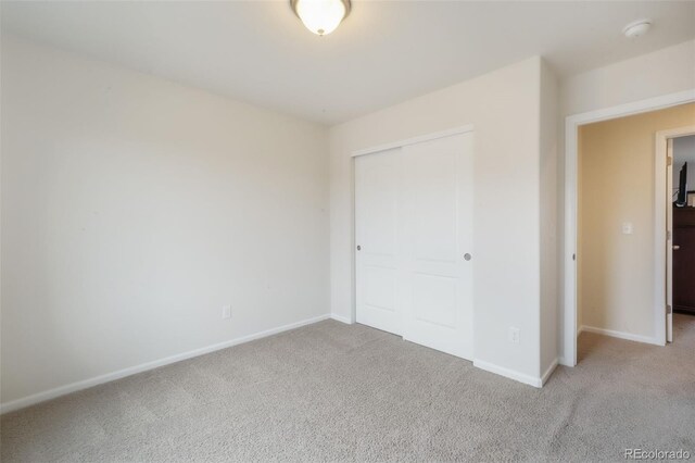 unfurnished bedroom featuring carpet, a closet, and baseboards