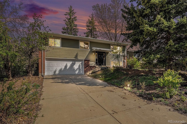 bi-level home featuring brick siding, a garage, and concrete driveway