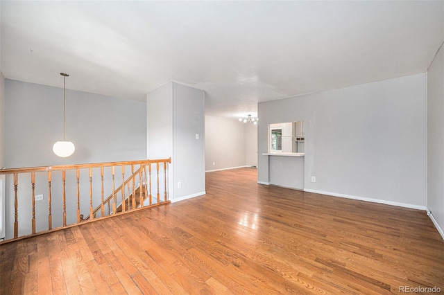 unfurnished room featuring baseboards, an inviting chandelier, and wood finished floors