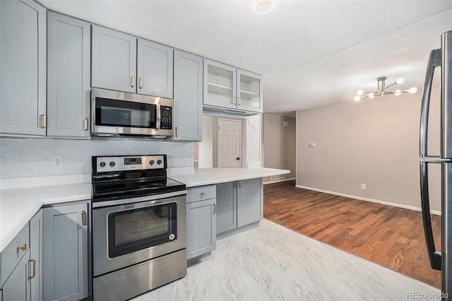 kitchen with light countertops, appliances with stainless steel finishes, gray cabinets, and glass insert cabinets