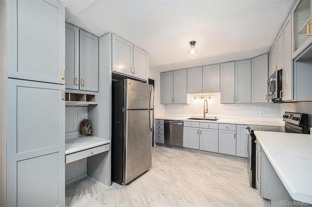 kitchen with gray cabinets, appliances with stainless steel finishes, decorative backsplash, and a sink