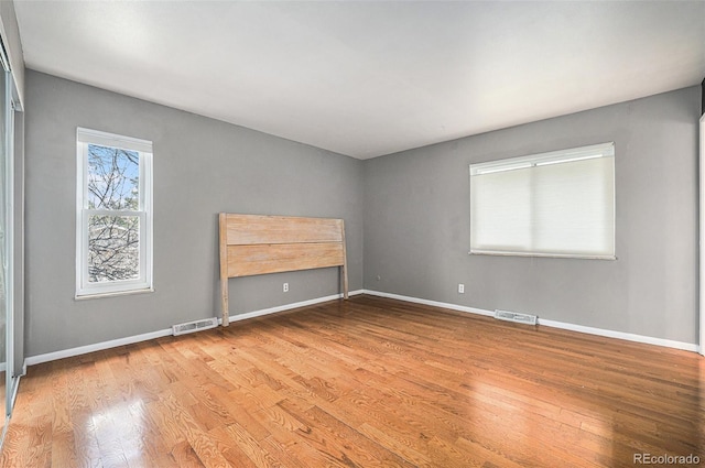 spare room with baseboards, wood finished floors, and visible vents