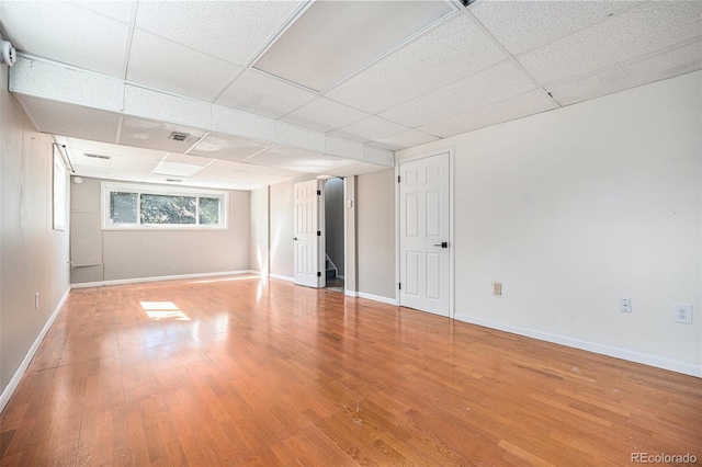 unfurnished room featuring baseboards, a drop ceiling, wood finished floors, and visible vents