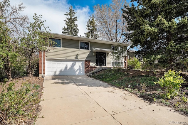 bi-level home featuring a garage, concrete driveway, and brick siding