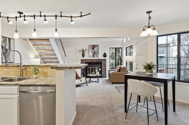 kitchen with stainless steel dishwasher, light colored carpet, plenty of natural light, and a sink