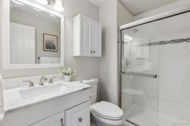 bathroom with vanity, a textured wall, toilet, and a shower stall