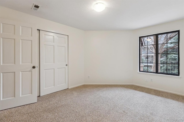 unfurnished bedroom featuring a closet, baseboards, visible vents, and light carpet