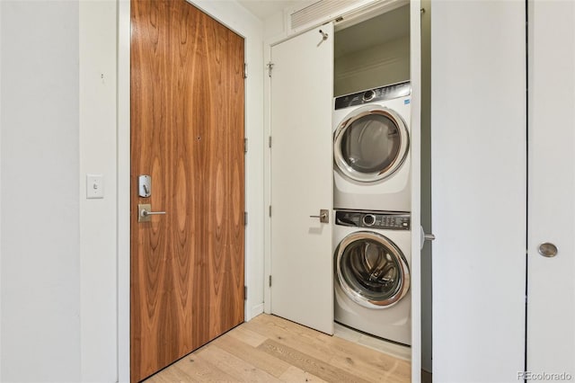 clothes washing area with stacked washing maching and dryer and light hardwood / wood-style floors