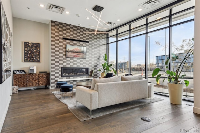 living room featuring expansive windows, visible vents, dark wood finished floors, and a tile fireplace