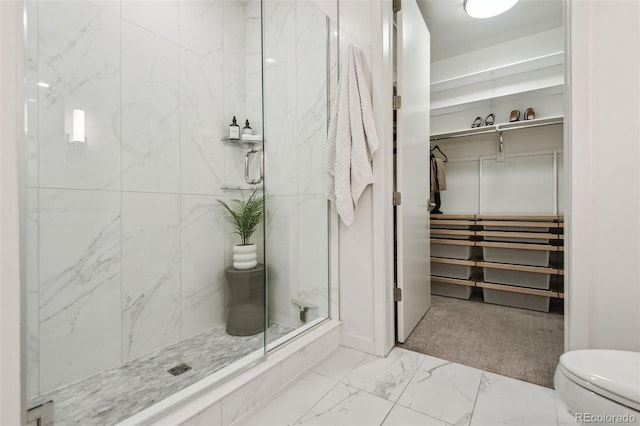 full bath featuring a stall shower, marble finish floor, a spacious closet, and toilet