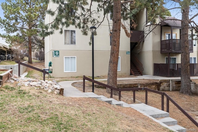 exterior space with stairs, fence, and stucco siding