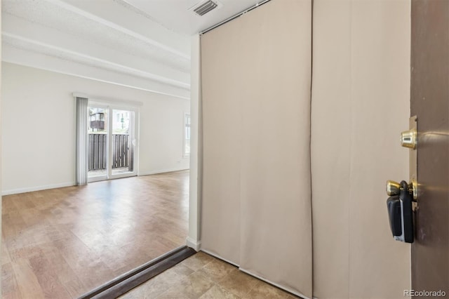 hallway featuring baseboards and visible vents