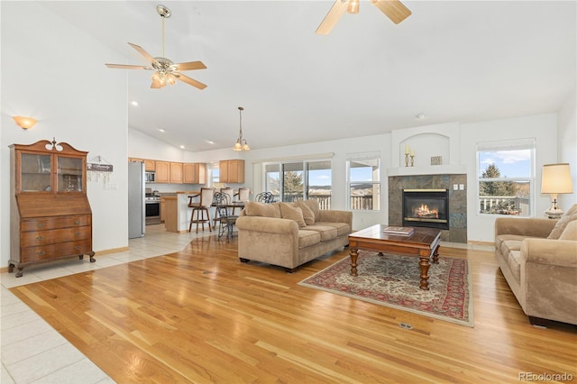 living room featuring a healthy amount of sunlight, light hardwood / wood-style floors, a tile fireplace, and high vaulted ceiling