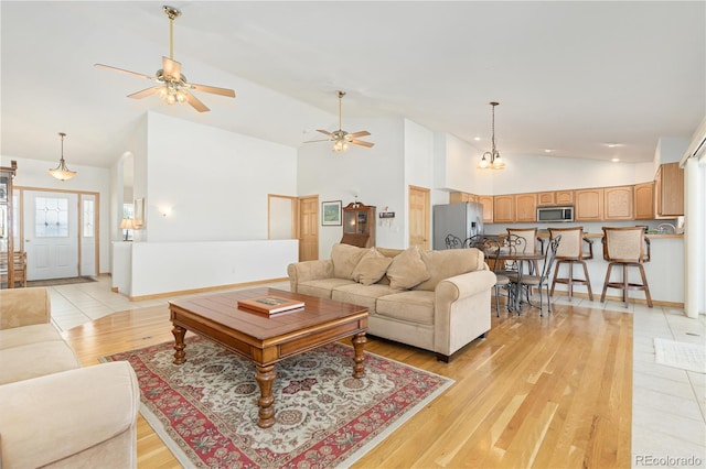 living room with light wood-type flooring, high vaulted ceiling, and ceiling fan