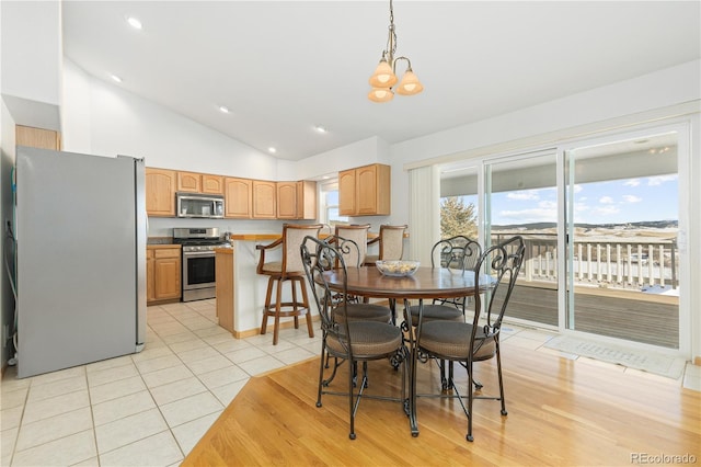 dining area featuring vaulted ceiling, an inviting chandelier, and light tile patterned floors