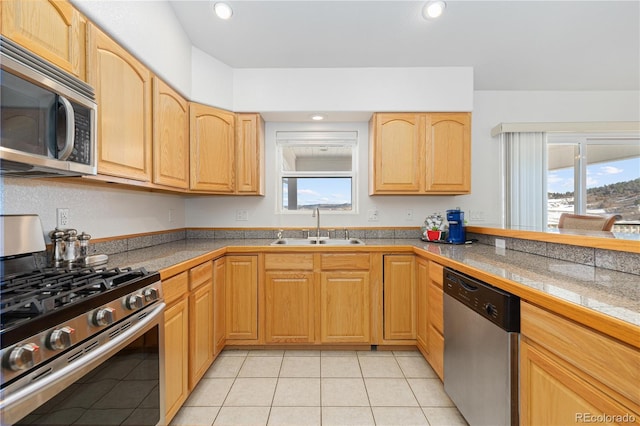 kitchen featuring appliances with stainless steel finishes, light tile patterned floors, a wealth of natural light, and sink