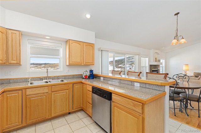 kitchen featuring dishwasher, a tiled fireplace, kitchen peninsula, a notable chandelier, and sink