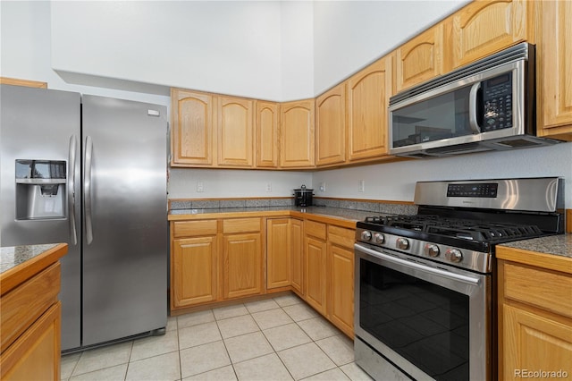 kitchen with stainless steel appliances, light brown cabinets, and light tile patterned floors