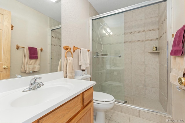 bathroom featuring toilet, a shower with door, tile patterned floors, and vanity