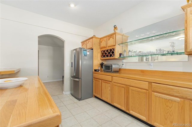 kitchen featuring light tile patterned floors, stainless steel fridge with ice dispenser, and wood counters