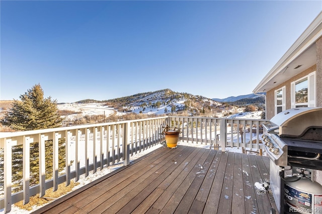 snow covered deck with a grill and a mountain view