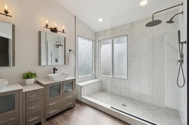full bathroom featuring vanity, wood finished floors, a marble finish shower, and lofted ceiling