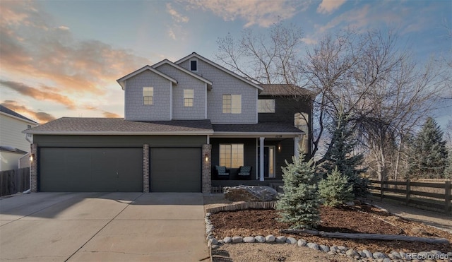 view of front of home featuring driveway, stone siding, an attached garage, a porch, and fence