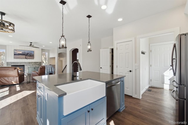 kitchen with arched walkways, blue cabinets, dark wood-style floors, and stainless steel appliances