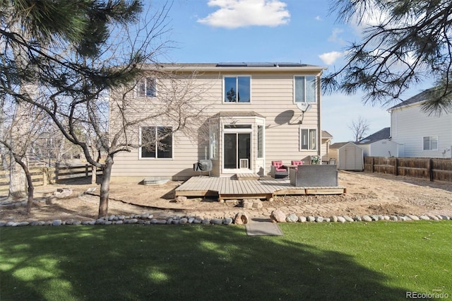 back of house with an outbuilding, a wooden deck, a storage shed, a yard, and fence