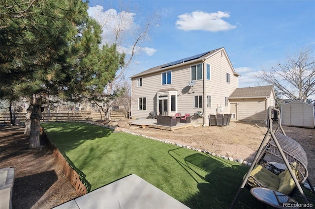 back of house with solar panels, a fenced backyard, an outdoor structure, a storage unit, and a wooden deck