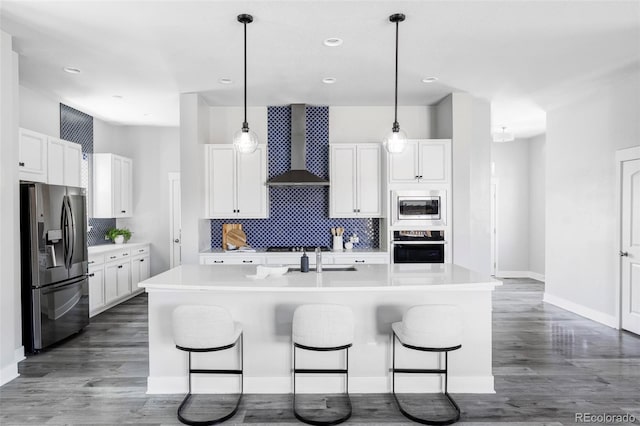 6037 N Netherland Ct, Aurora, CO 80019 - kitchen featuring appliances with stainless steel finishes, wall chimney range hood, tasteful backsplash, white cabinetry, and recessed lighting