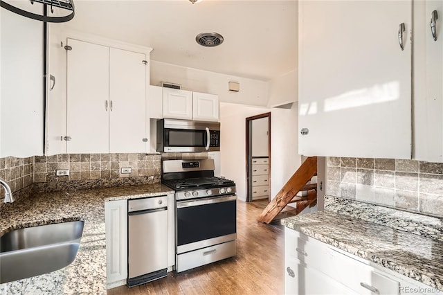 kitchen featuring tasteful backsplash, stainless steel appliances, sink, hardwood / wood-style flooring, and white cabinetry