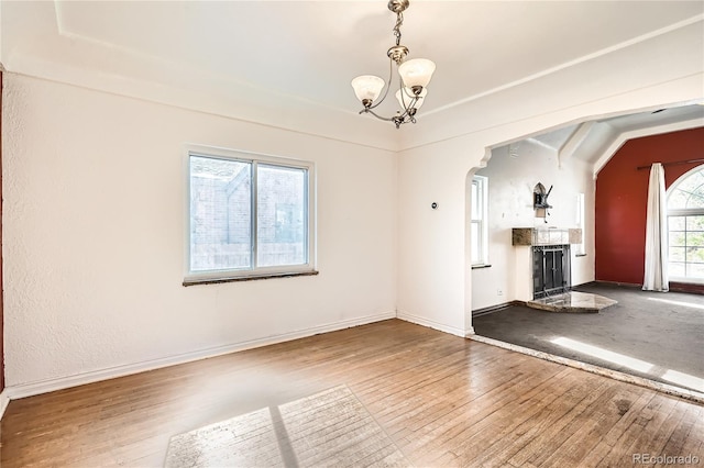 unfurnished living room featuring hardwood / wood-style flooring, a notable chandelier, and lofted ceiling